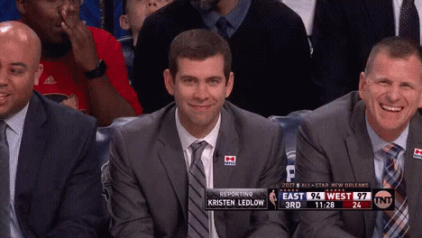 A Man In A Suit And Tie Is Smiling While Sitting In The Stands During A Basketball Game GIF