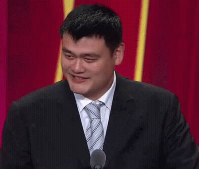 A Man In A Suit And Tie Is Smiling While Speaking Into A Microphone GIF