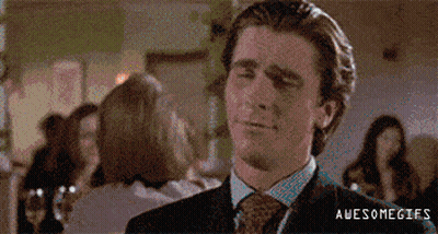 A Man In A Suit And Tie Is Smiling While Standing In A Crowded Room . GIF