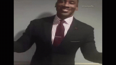 A Man In A Suit And Tie Is Smiling With His Arms Outstretched . GIF