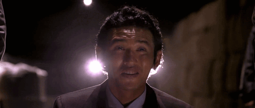 A Man In A Suit And Tie Is Smiling With His Hand Outstretched GIF