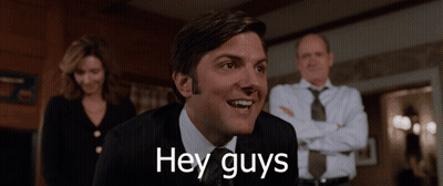 A Man In A Suit And Tie Is Smiling With The Words Hey Guys Below Him GIF