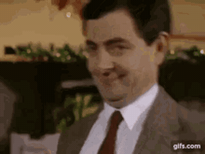 A Man In A Suit And Tie Is Smiling . GIF