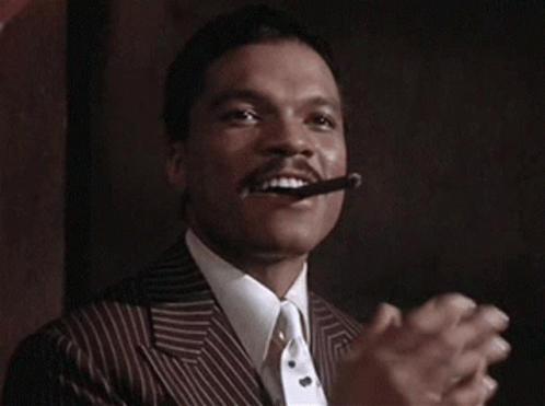 A Man In A Suit And Tie Is Smoking A Cigar And Holding A Stack Of Money . GIF