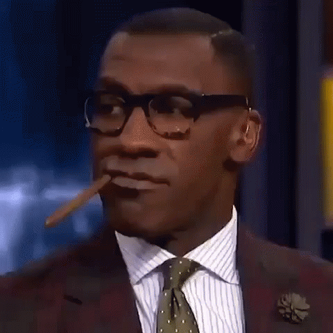A Man In A Suit And Tie Is Smoking A Cigar And Making A Funny Face . GIF