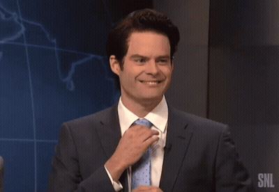 A Man In A Suit And Tie Is Speaking Into A Microphone With The Snl Logo In The Background GIF