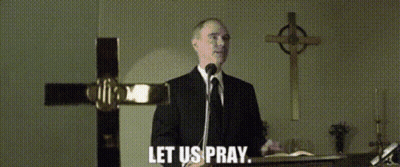 A Man In A Suit And Tie Is Speaking Into A Microphone With The Words Let Us Pray Below Him GIF
