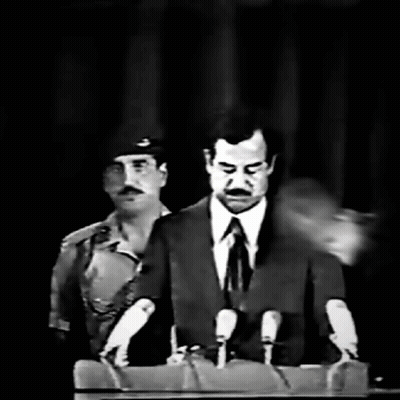 A Man In A Suit And Tie Is Speaking Into Microphones GIF