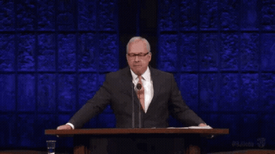 A Man In A Suit And Tie Is Standing At A Podium Giving A Speech And The Word Liar Is Above Him . GIF
