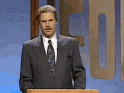 A Man In A Suit And Tie Is Standing Behind A Podium GIF