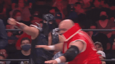 A Man In A Suit And Tie Is Standing Behind Two Wrestlers GIF