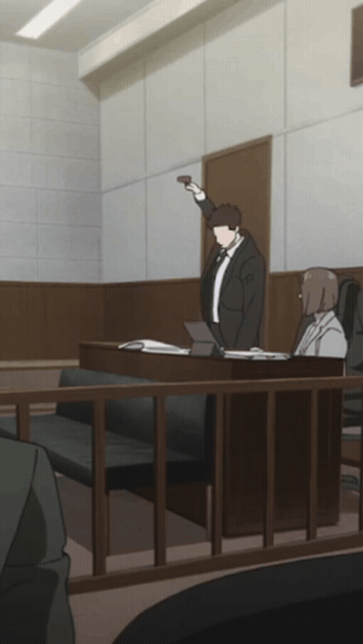 A Man In A Suit And Tie Is Standing In A Courtroom Holding Up A Gun GIF