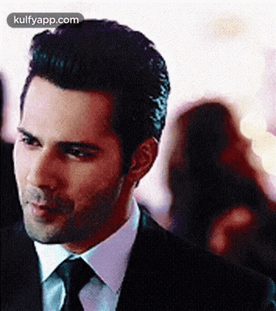 A Man In A Suit And Tie Is Standing In A Crowd . GIF