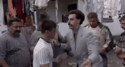 A Man In A Suit And Tie Is Standing In A Crowd Of Men . GIF
