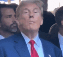 A Man In A Suit And Tie Is Standing In A Crowd Of People . GIF