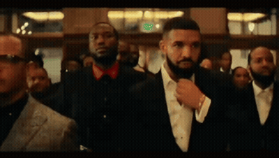 A Man In A Suit And Tie Is Standing In A Crowd Of People . GIF