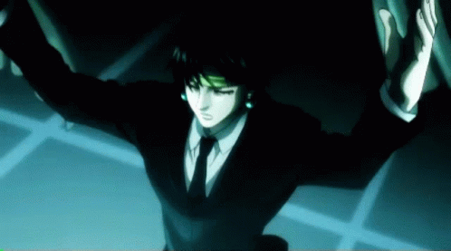A Man In A Suit And Tie Is Standing In A Dark Room GIF