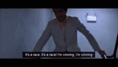 A Man In A Suit And Tie Is Standing In A Dark Room Holding A Gun And Talking . GIF
