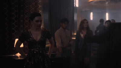A Man In A Suit And Tie Is Standing In A Dark Room GIF
