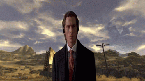 A Man In A Suit And Tie Is Standing In A Desert GIF
