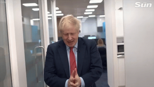A Man In A Suit And Tie Is Standing In A Doorway And Smiling . GIF