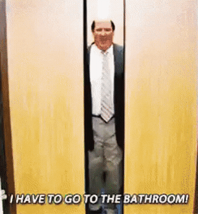 A Man In A Suit And Tie Is Standing In A Doorway With The Words `` I Have To Go To The Bathroom ! '' GIF