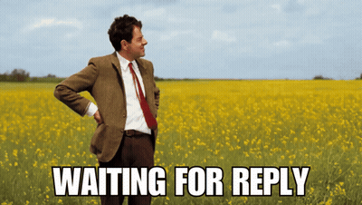 A Man In A Suit And Tie Is Standing In A Field Of Yellow Flowers With The Words Waiting For Reply Above Him GIF