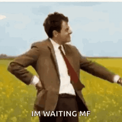 A Man In A Suit And Tie Is Standing In A Field With His Hands On His Back . GIF