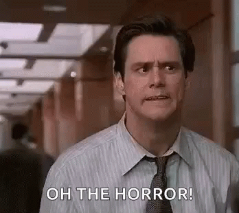 A Man In A Suit And Tie Is Standing In A Hallway And Saying `` Oh The Horror '' . GIF