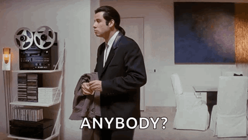 A Man In A Suit And Tie Is Standing In A Living Room Holding His Jacket And Asking , `` Anybody ? '' GIF