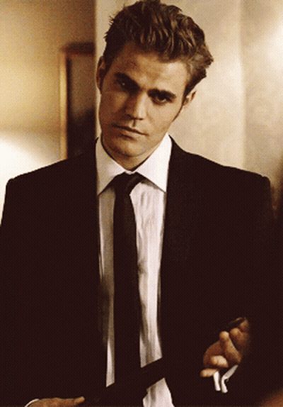 A Man In A Suit And Tie Is Standing In A Room GIF