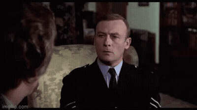 A Man In A Suit And Tie Is Standing In A Room And Making A Funny Face . GIF
