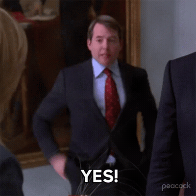 A Man In A Suit And Tie Is Standing In A Room And Says Yes . GIF