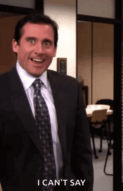 A Man In A Suit And Tie Is Standing In A Room And Smiling . GIF