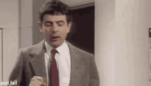 A Man In A Suit And Tie Is Standing In A Room . GIF