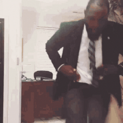 A Man In A Suit And Tie Is Standing In A Room . GIF