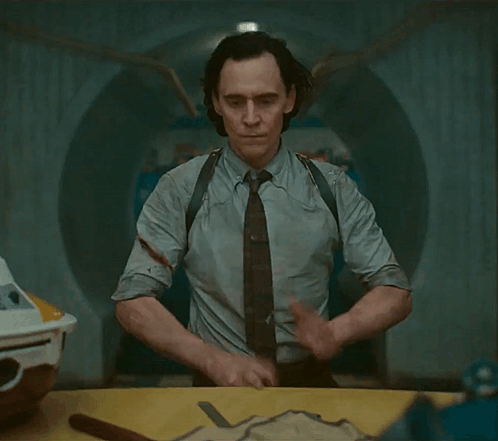 A Man In A Suit And Tie Is Standing In A Room GIF