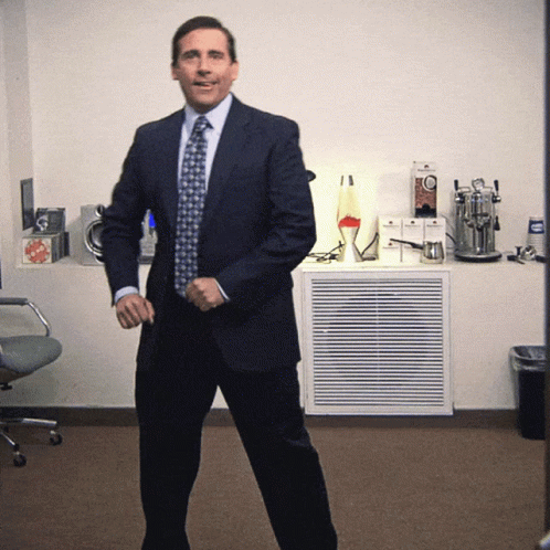 A Man In A Suit And Tie Is Standing In A Room GIF