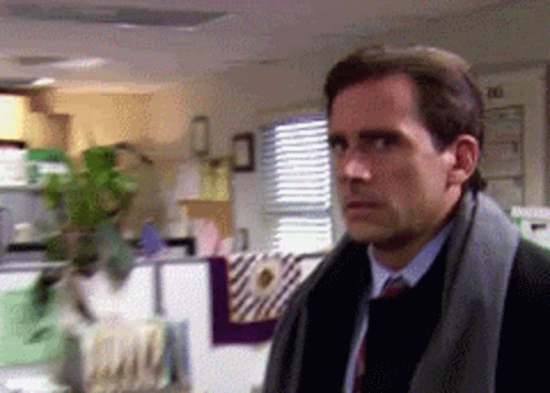 A Man In A Suit And Tie Is Standing In A Room With A Calendar On The Wall GIF