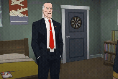 A Man In A Suit And Tie Is Standing In A Room With A Dart Board On The Door GIF