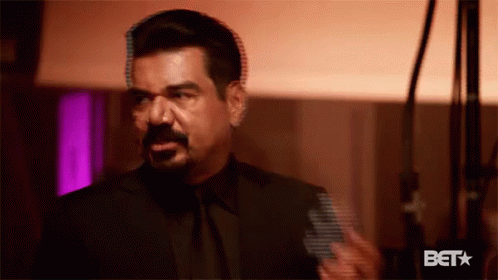 A Man In A Suit And Tie Is Standing In A Room With A Microphone . GIF