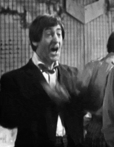 A Man In A Suit And Tie Is Standing In A Room With His Mouth Open . GIF