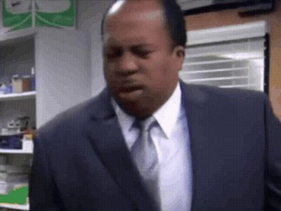 A Man In A Suit And Tie Is Standing In A Room With His Mouth Open . GIF