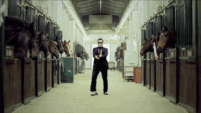 A Man In A Suit And Tie Is Standing In A Stable Surrounded By Horses GIF