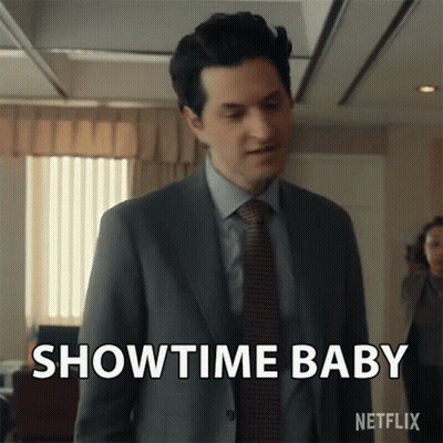 A Man In A Suit And Tie Is Standing In An Office And Says Showtime Baby . GIF