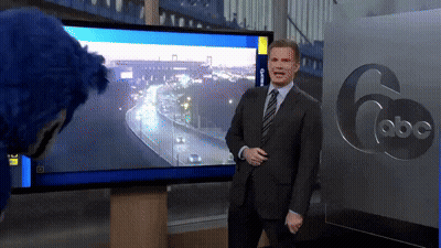 A Man In A Suit And Tie Is Standing In Front Of A Abc Sign GIF