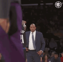 A Man In A Suit And Tie Is Standing In Front Of A Basketball Player Wearing A Jersey With The Number 21 On It GIF