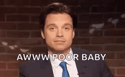 A Man In A Suit And Tie Is Standing In Front Of A Brick Wall And Talking Into A Microphone . GIF
