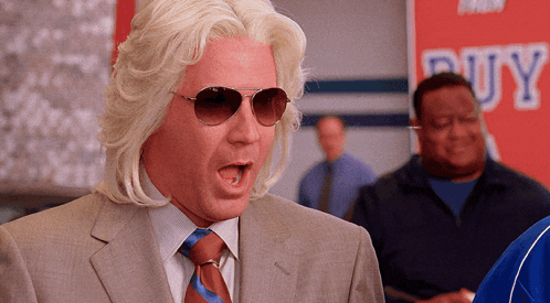 A Man In A Suit And Tie Is Standing In Front Of A Buy Sign GIF