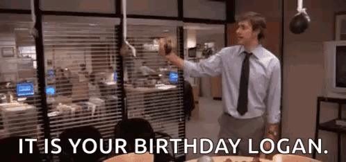 A Man In A Suit And Tie Is Standing In Front Of A Cake In An Office . GIF